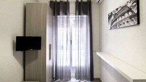 A room with a TV mounted on the wall, a painting of the Colosseum, a wardrobe, and a curtain. - Roema Guest House (Rome)