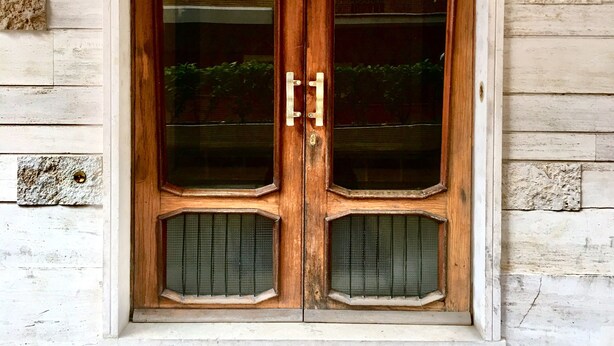 A wooden double door with glass panels and a stone base. - Roema Guest House (Rome)