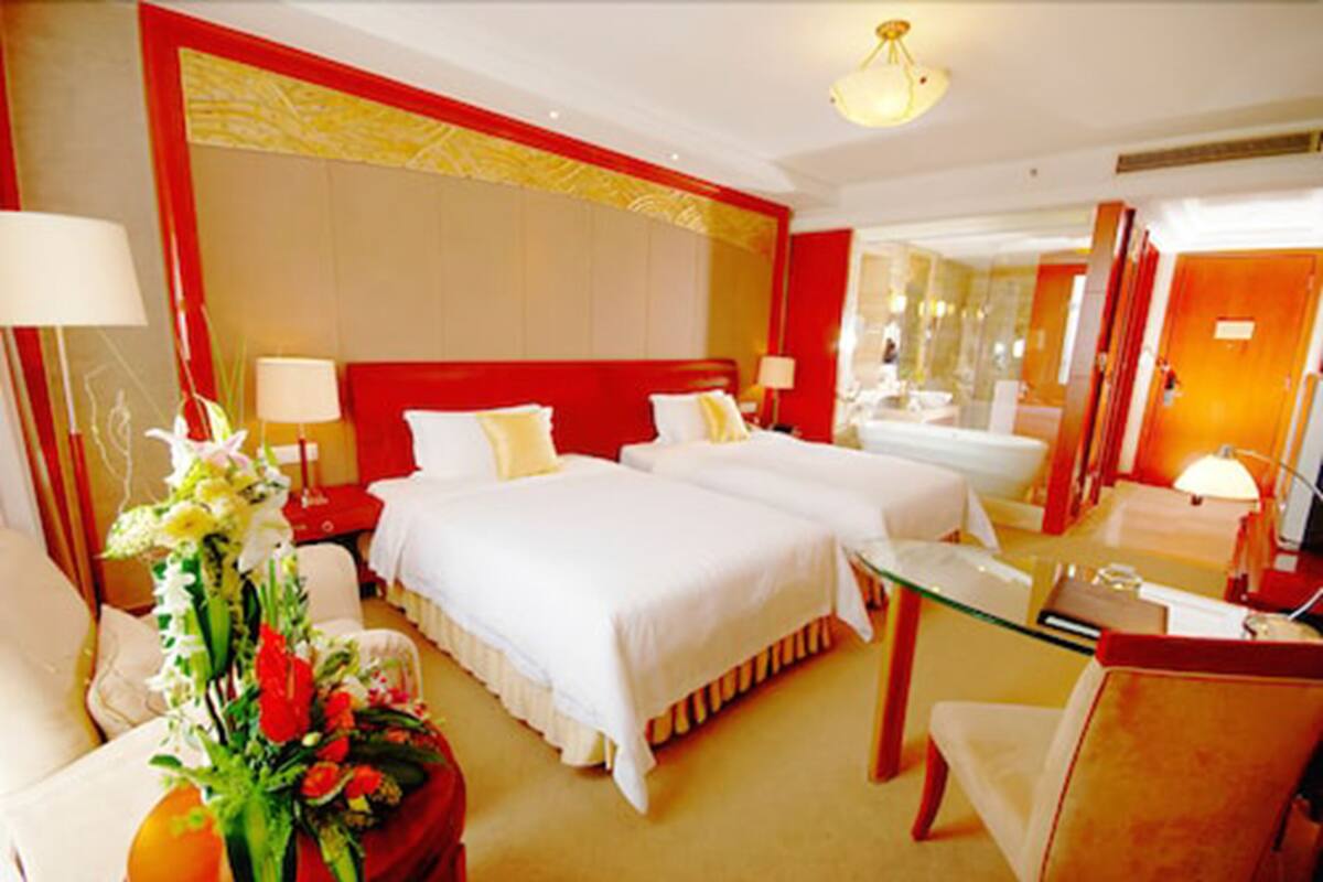 A hotel room with two beds, a glass desk, and a mirror.