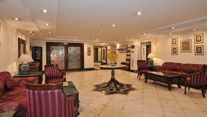 A spacious lobby with a marble floor, red upholstered sofas, and a central decorative table. - Qutub Residency (New Delhi)