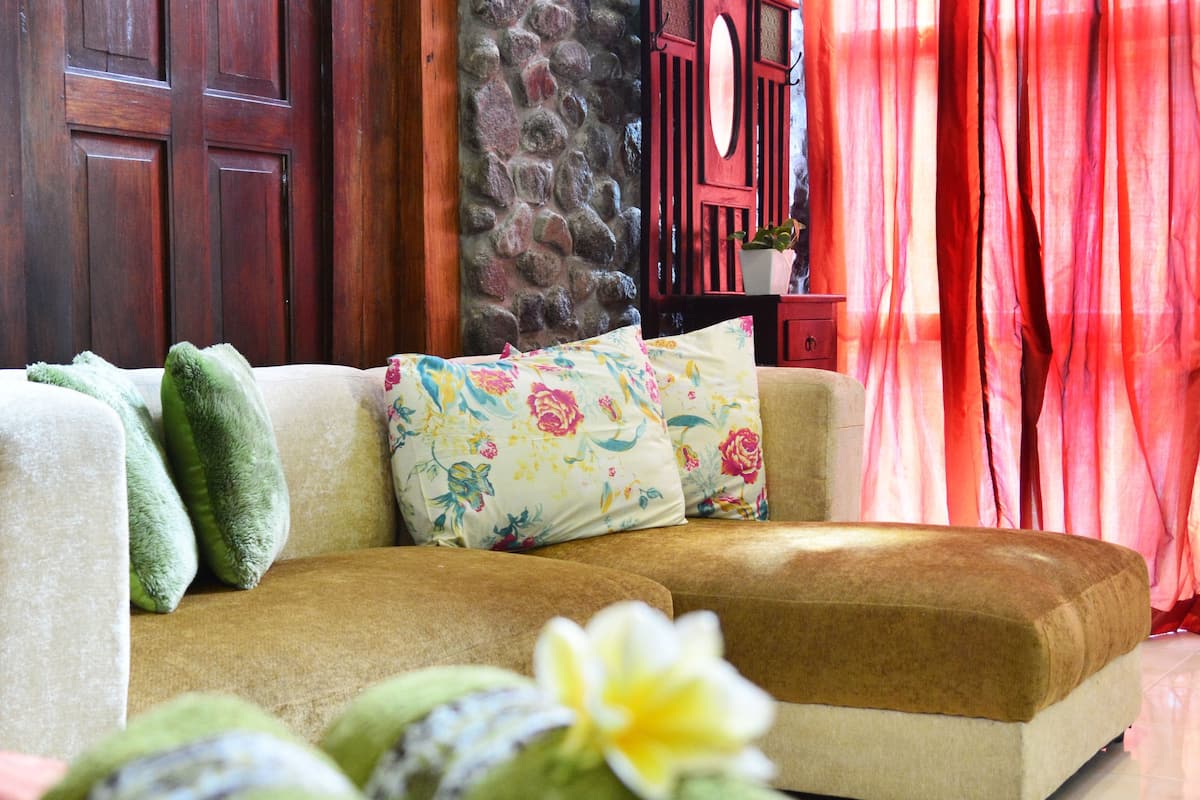 A cozy room with a sofa, pillows, and rolled towels.