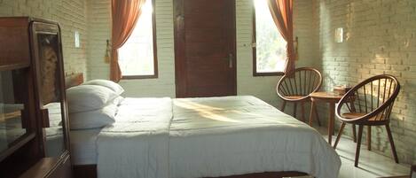 Una habitación con una cama, dos sillas de madera, una mesita y un televisor.