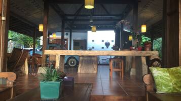 Un hall d’entrée spacieux avec un plafond haut, des meubles en bois et une table centrale.