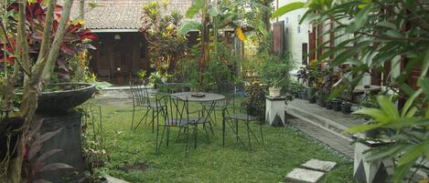 A garden with a table and chairs, surrounded by potted plants and a stone pathway.
