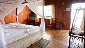 A room with a bed under a mosquito net, a television, a wooden desk, and a chair. - Shiny Lakeside Resort (Hikkaduwa)