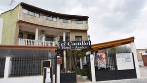 A hotel named "el Castillo Hotel - Asador" with a balcony, a gated entrance, and a signboard. - El Castillo (Larraga)