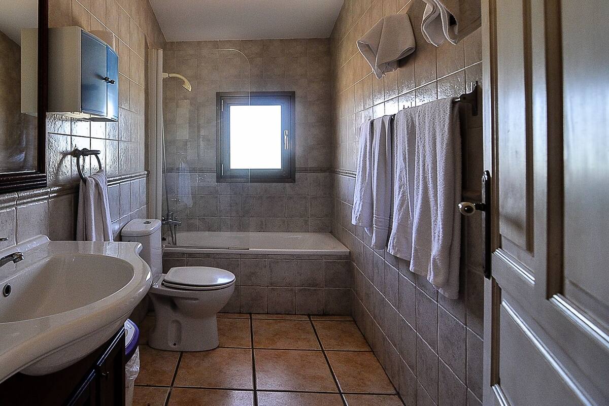 A bathroom with a sink, toilet, bathtub, and a window.