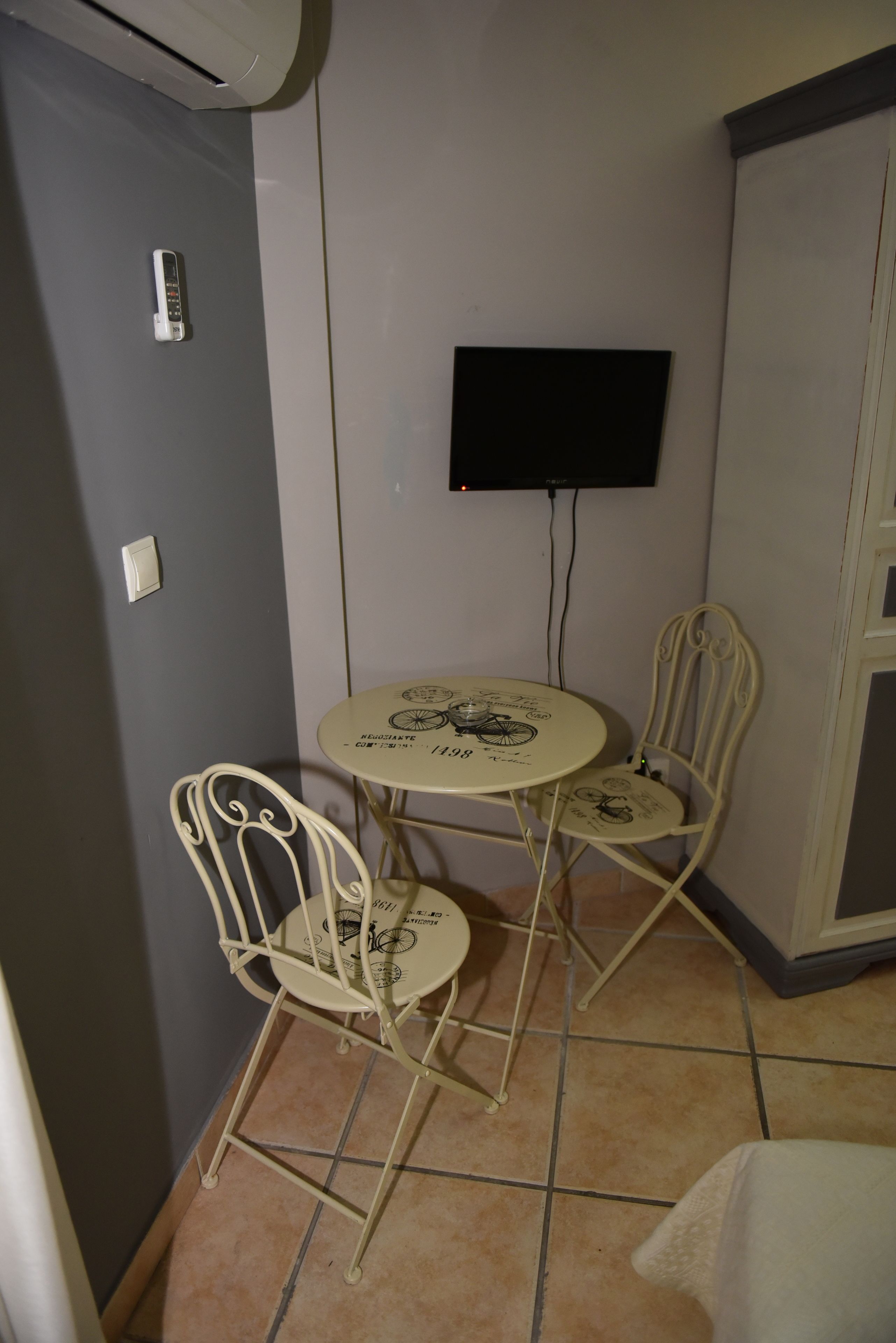 A small room with a table and two chairs, a flat-screen TV mounted on the wall, and a door.