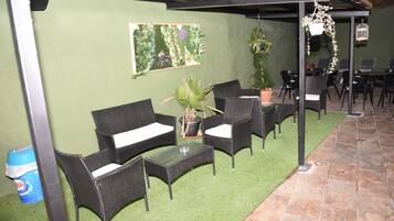 Un patio al aire libre con mobiliario de mimbre, una pequeña mesa y plantas en macetas.