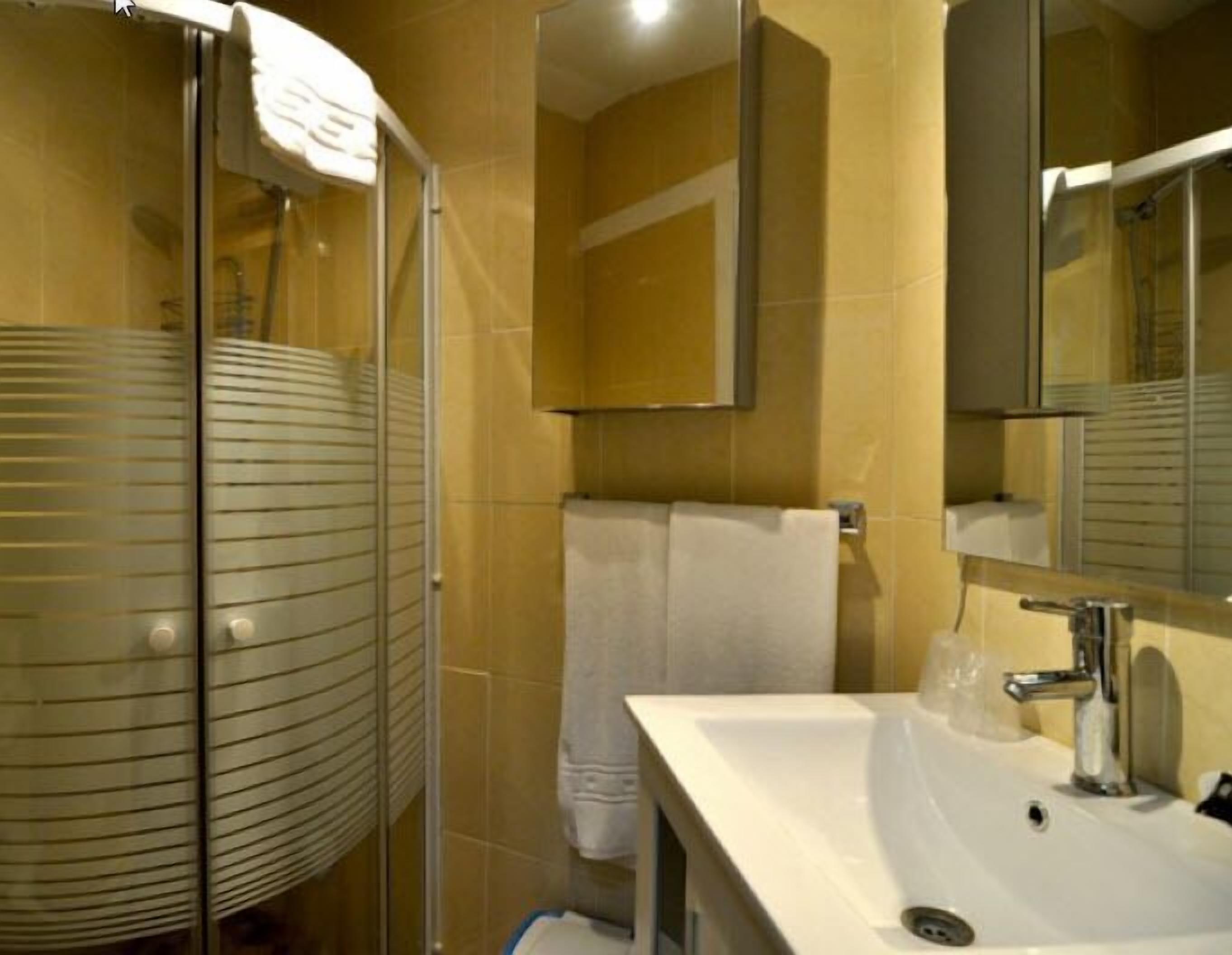 Un baño con cabina de ducha de vidrio, un lavabo blanco y un espejo.