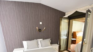 A hotel room with a bed, a nightstand, a mirror, and a sliding door leading to a bathroom. - El Castillo (Larraga)