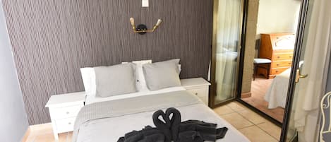 Habitación de hotel con cama, mesita de noche, espejo y puerta corredera que da a un baño.