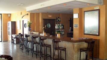 A bar area with a counter, stools, and a wall-mounted TV.
