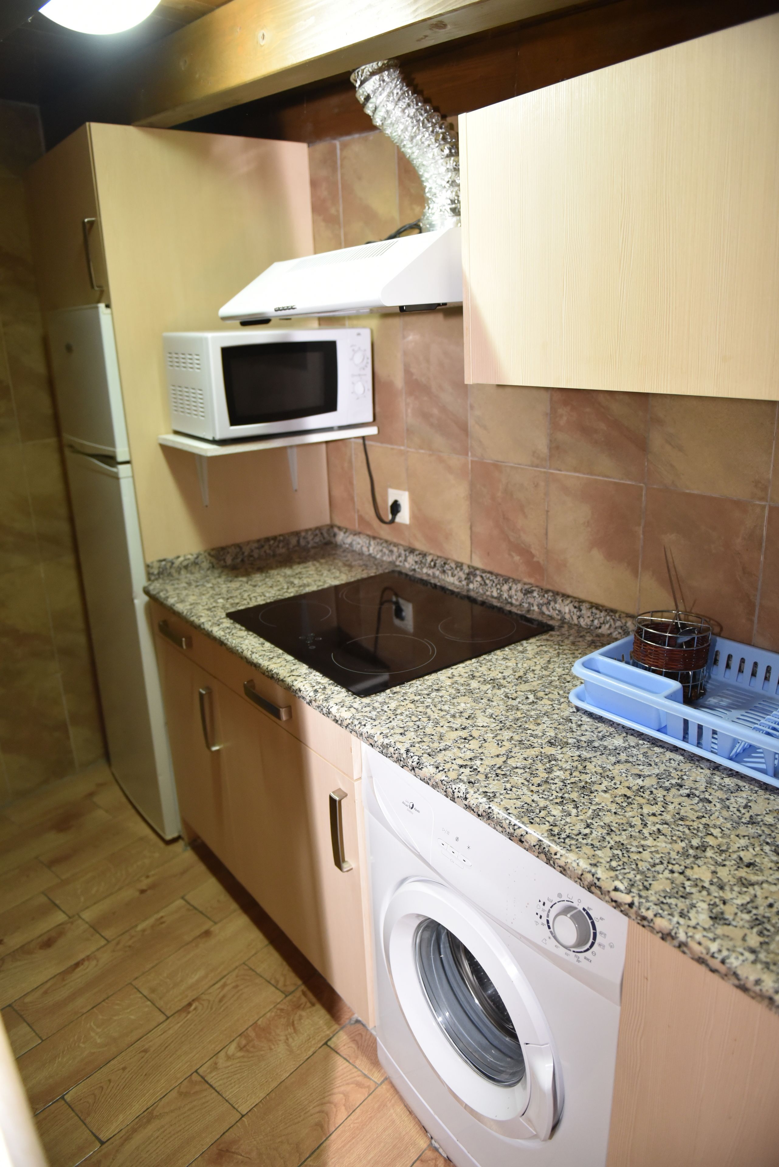 A compact kitchen with a built-in microwave, a sink, and a washing machine.