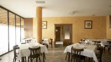 Una zona de dinar amb taules preparades per al servei, un ample pilaret i obra d'art emmarcada a les parets.