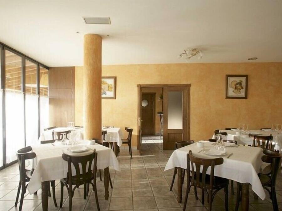 Una zona de dinar amb taules preparades per al servei, un ample pilaret i obra d'art emmarcada a les parets.