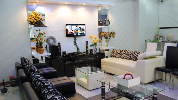 A modern living room with a sofa, coffee table, and TV. - Rene Hotel (Yogyakarta)