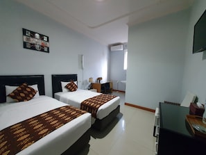 Una habitación de hotel con dos camas, un escritorio, una silla, un televisor y una ventana.