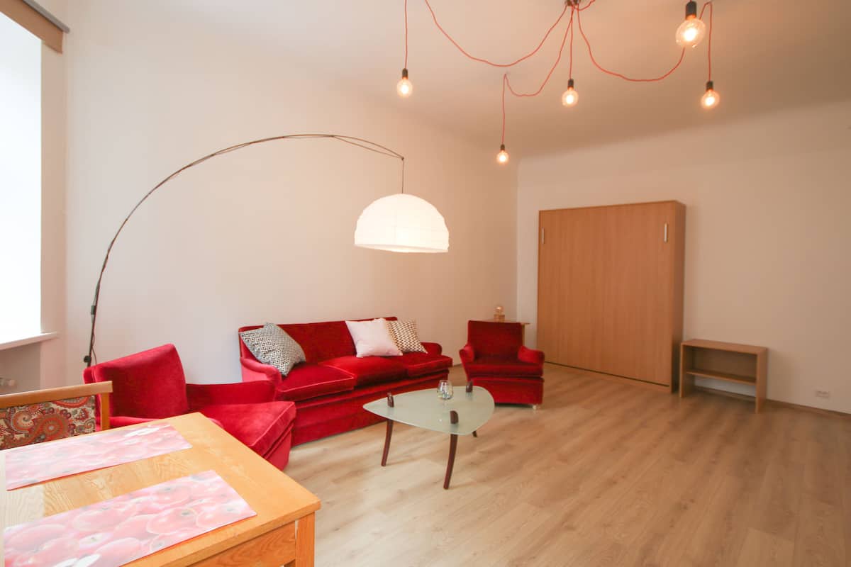 A modern living room with a red sofa, a glass coffee table, and a wooden cabinet.