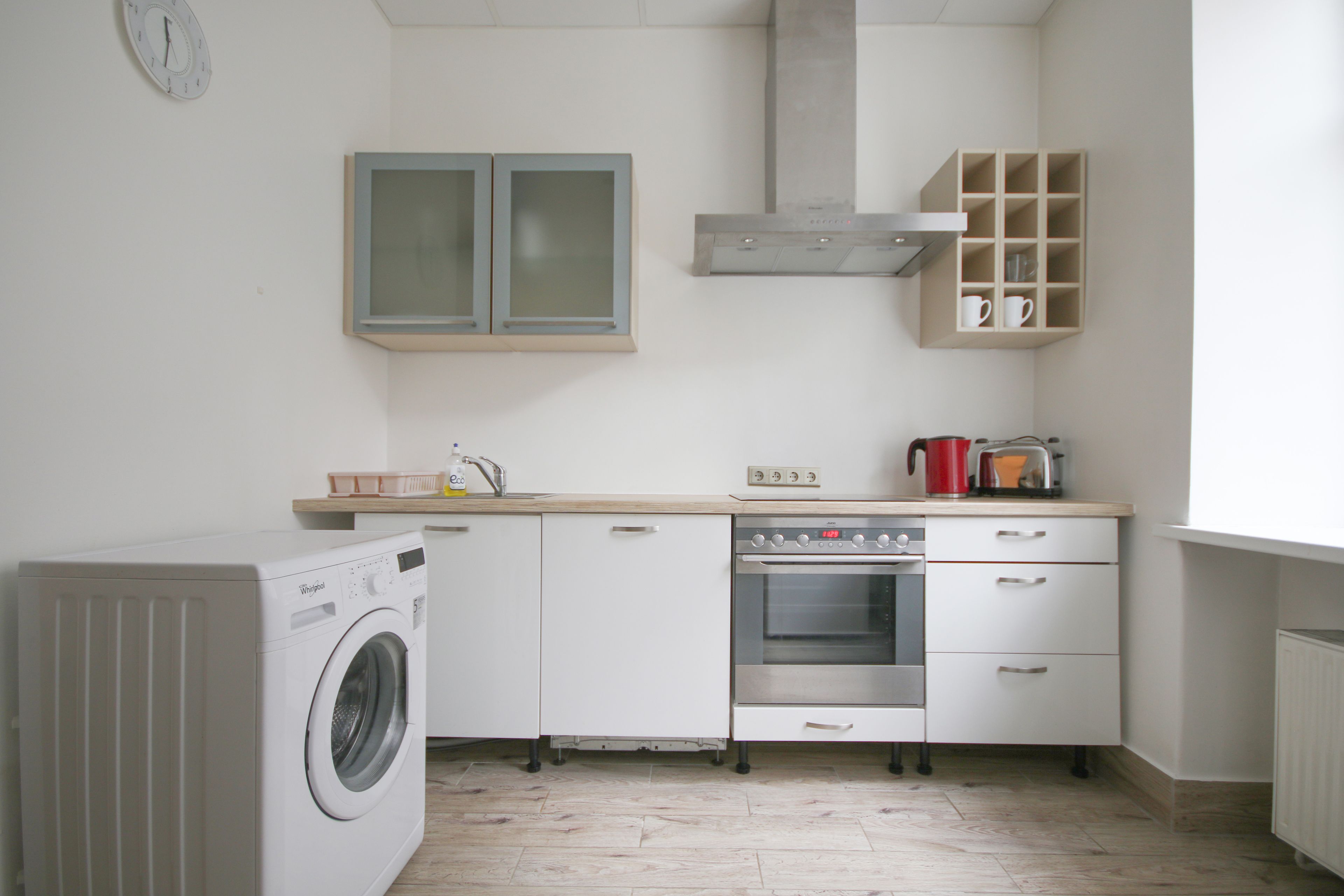 A compact kitchen with a washing machine, a stove, and a microwave.