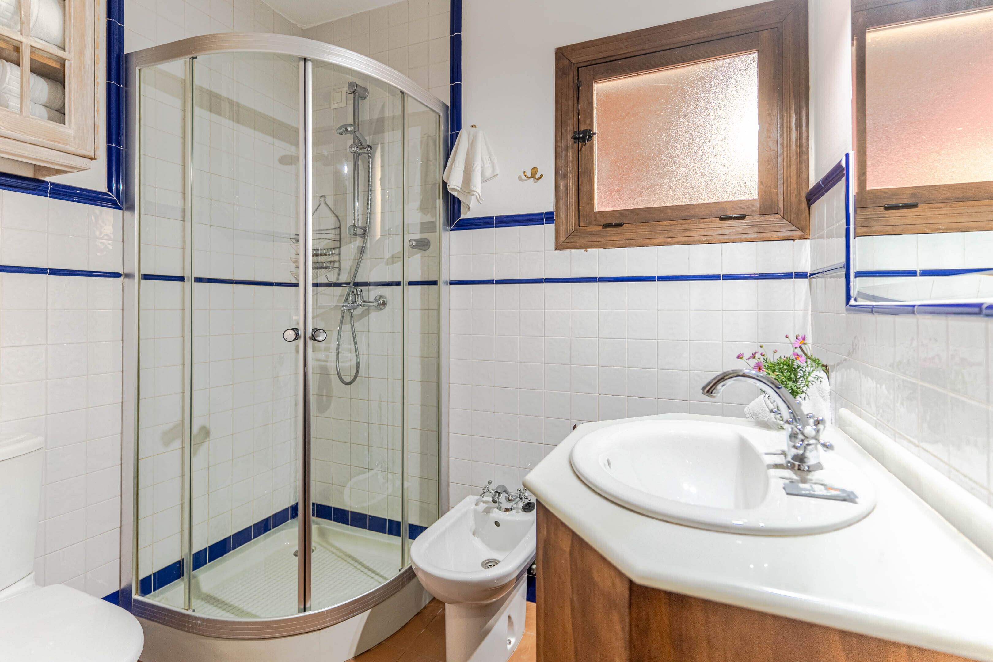 A bathroom with a glass-enclosed shower, a sink with a mirror above it, and a wooden cabinet.