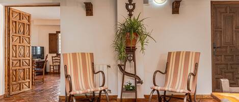 A room with two rocking chairs, a potted plant, and a wooden door.