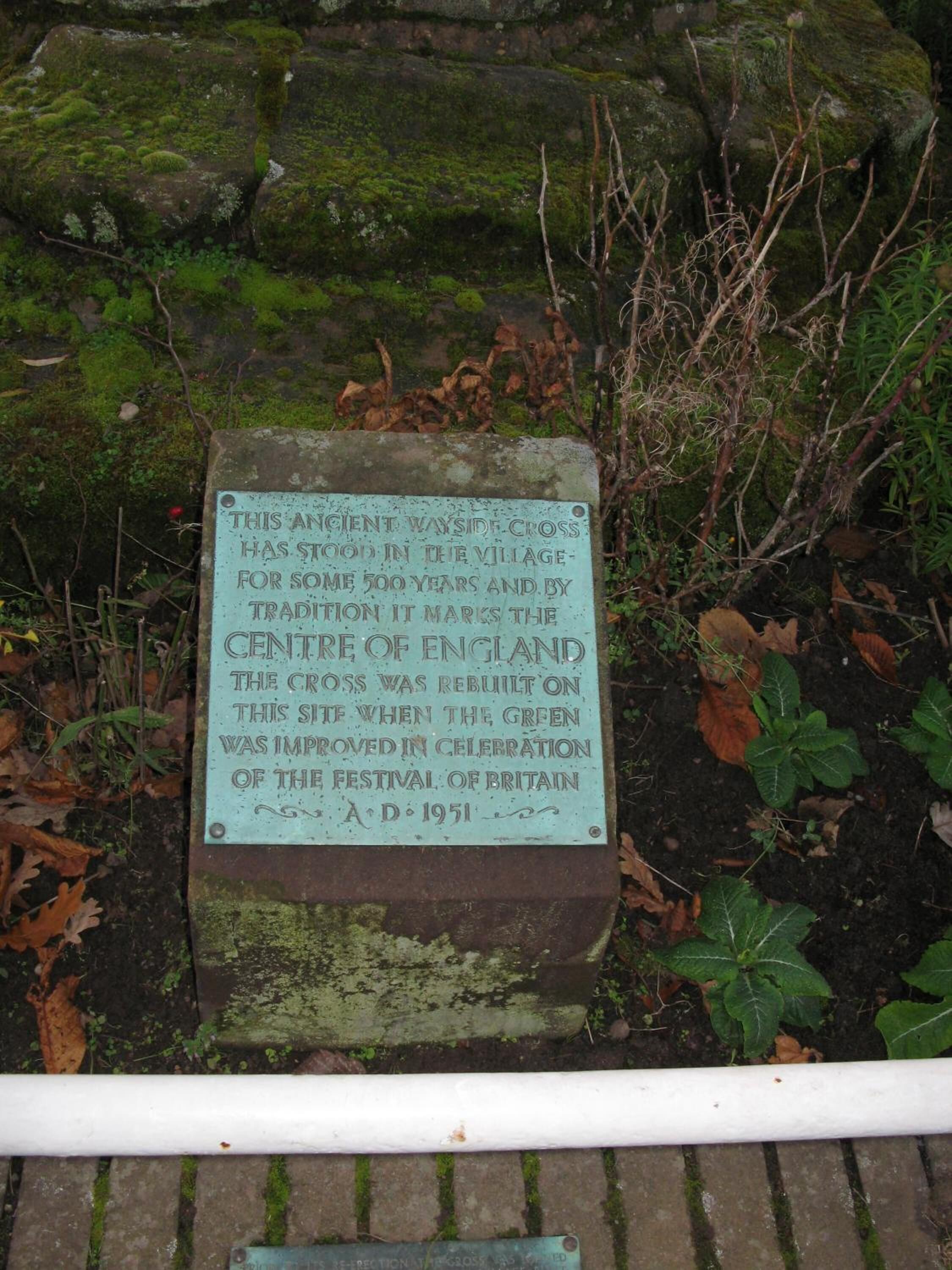 A historical stone plaque with text, surrounded by moss and vegetation.