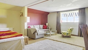 A room with a bed, a sofa, a chair, and a window with curtains.