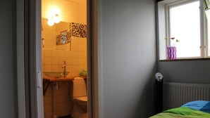 A small, compact room with a bed, a window with a view, a sink, and a toilet.