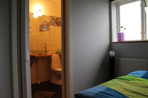 Cozy room with a single bed, window, and bathroom facilities.