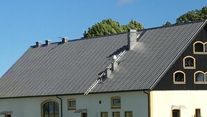 A farmhouse with a sloped roof and a large field of crops in the foreground.