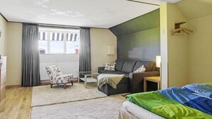 A compact hotel room with a sofa, a small table, a chair, and a bed. - Hotel Borrby (Borrby)
