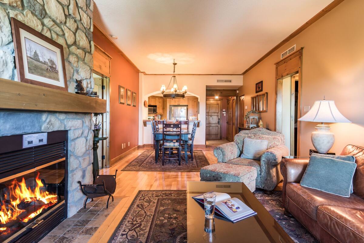 A cozy living room with a fireplace, a dining area, and a leather sofa.
