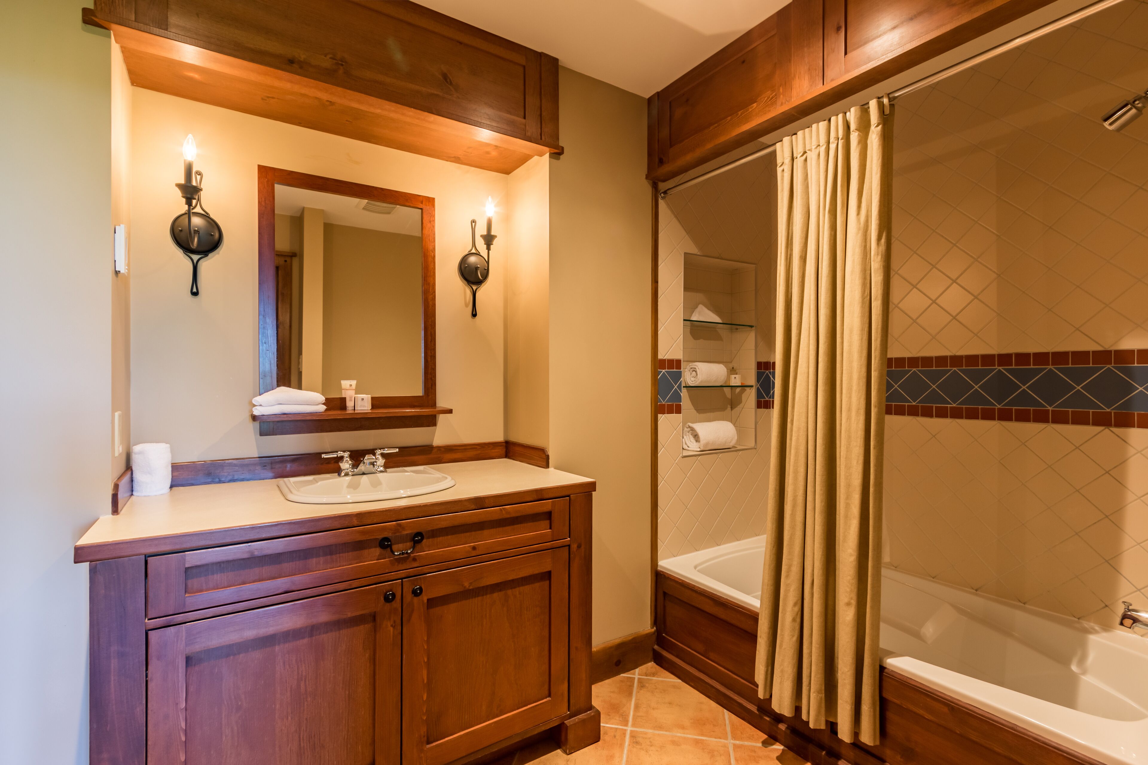 A bathroom with wooden cabinetry, a sink, a mirror, and a bathtub with a shower curtain.