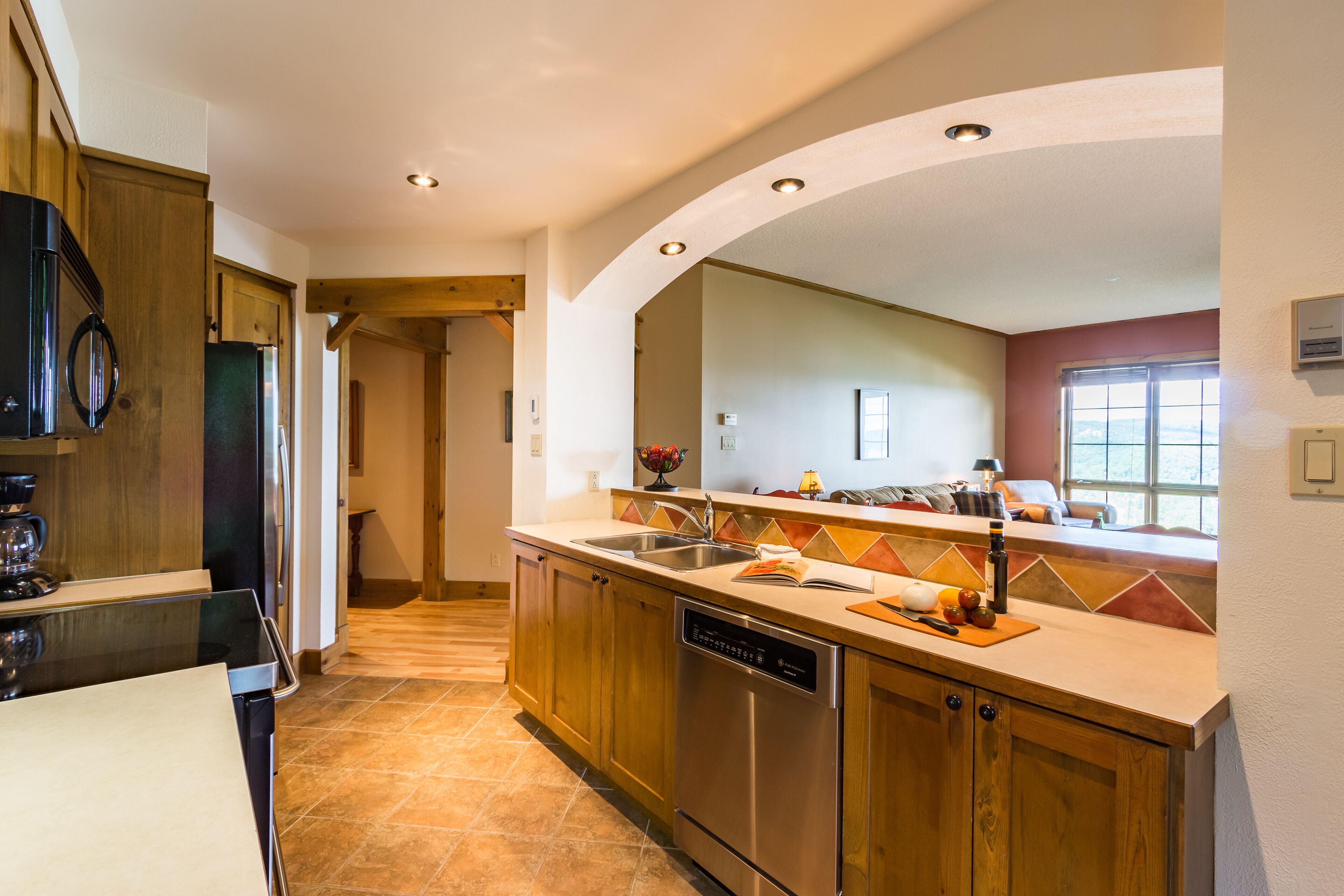 Una cucina moderna con mobili in legno, elettrodomestici in acciaio inossidabile e una parete rivestita di piastrelle.