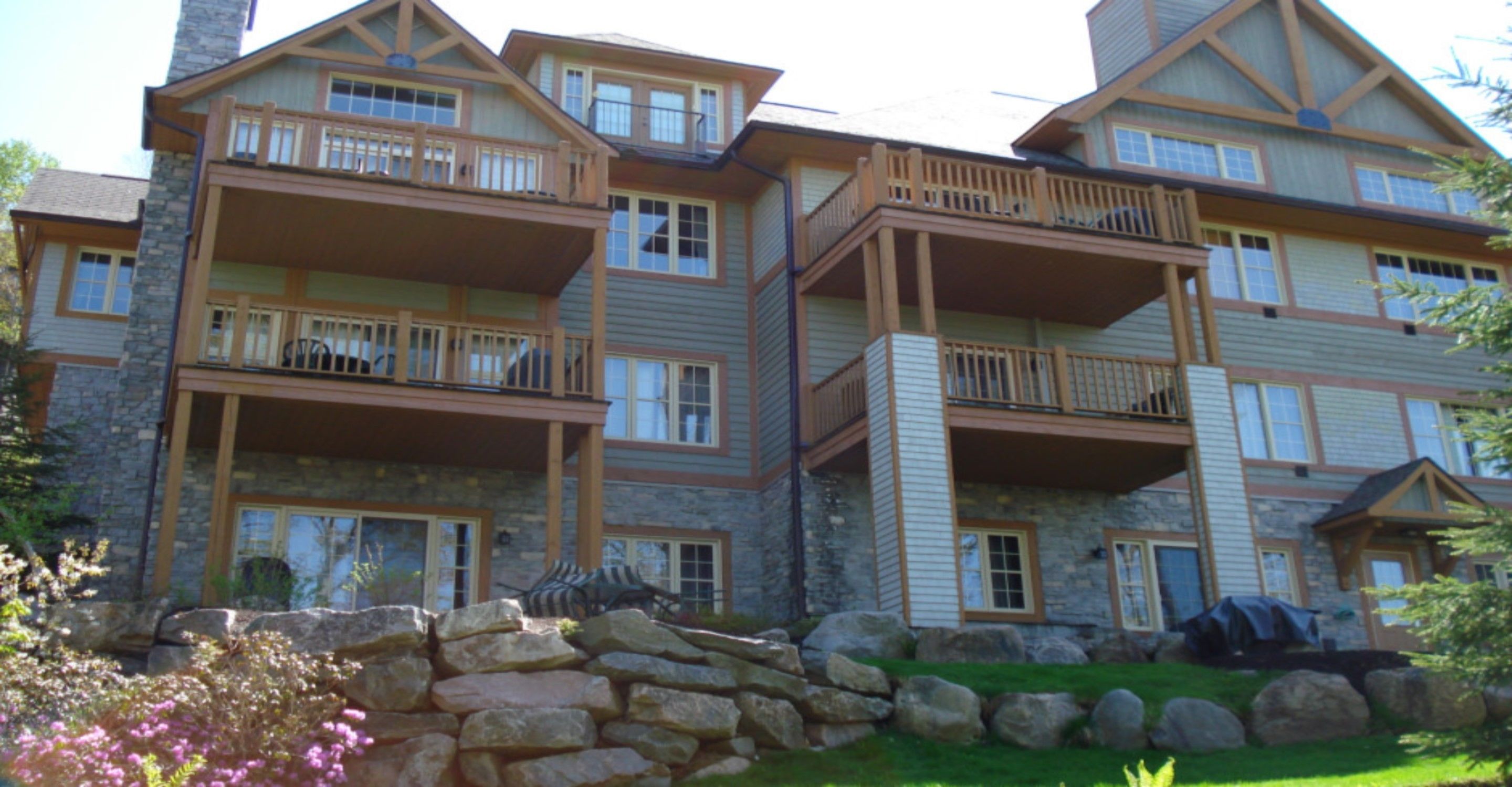 A multi-story building with balconies, stone facade, and a stone retaining wall.
