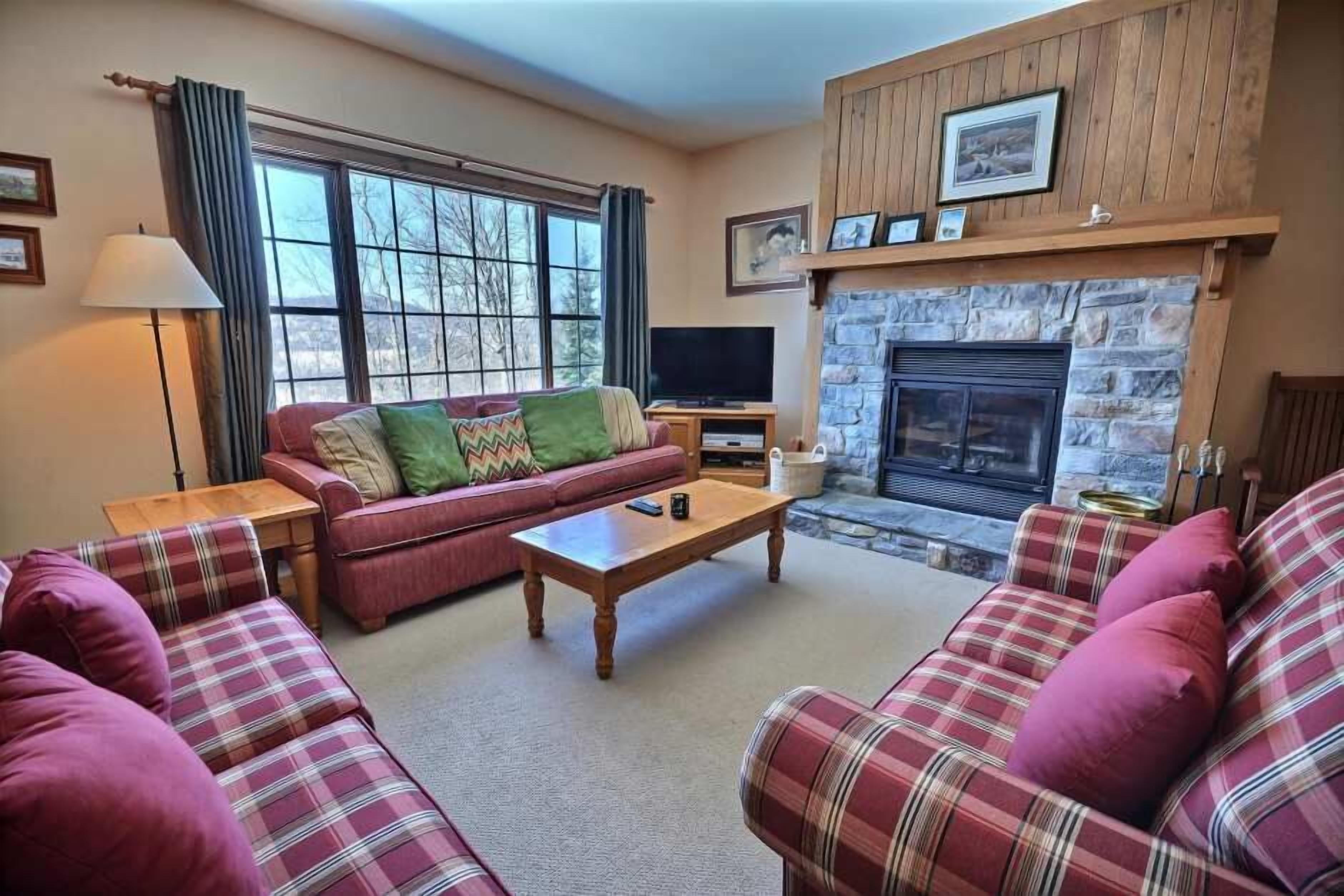 A cozy living room with a fireplace, a sofa set, and a television.