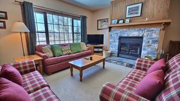 A cozy living room with a fireplace, a sofa set, and a television.