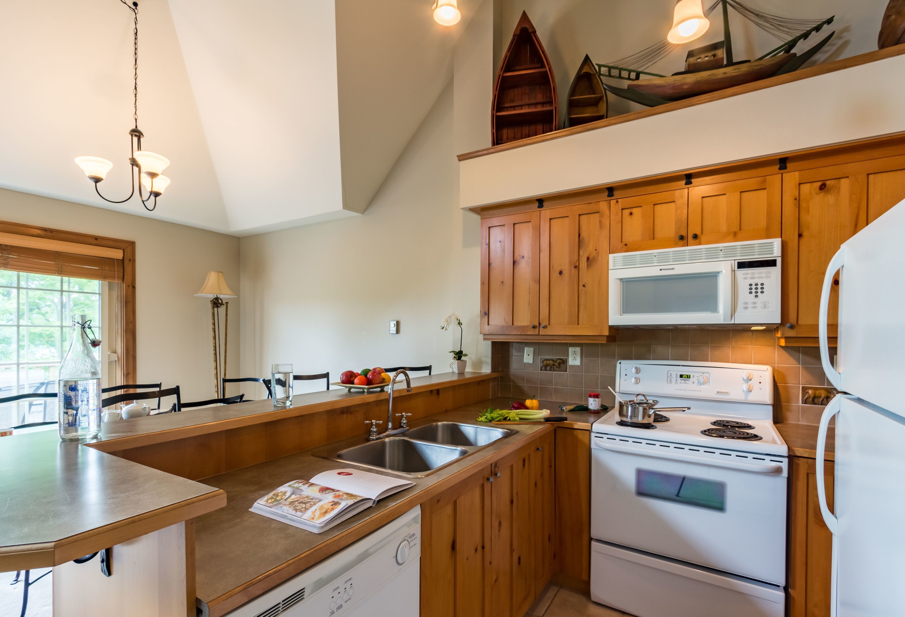 A kitchen with wooden cabinets, a microwave, a stove, and a sink.
