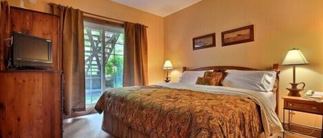A bedroom with a bed, two bedside lamps, a TV, and a wooden cabinet.