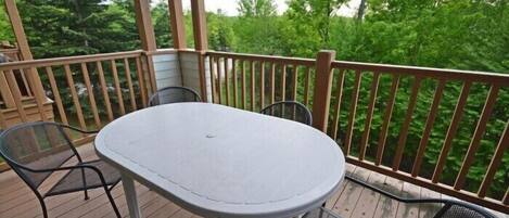 A covered outdoor deck with a round table and two chairs.