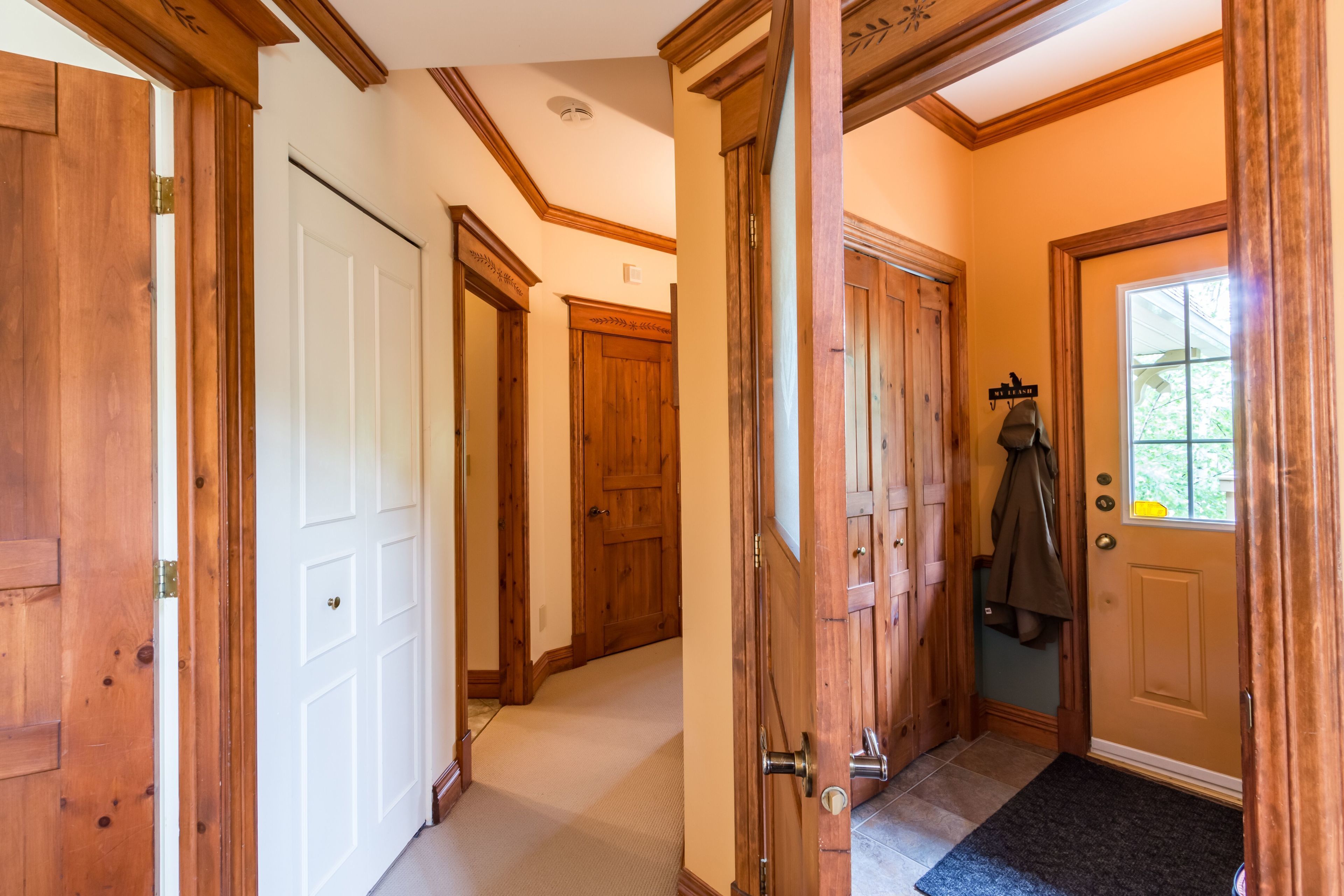 A hallway with wooden doors and a coat rack.