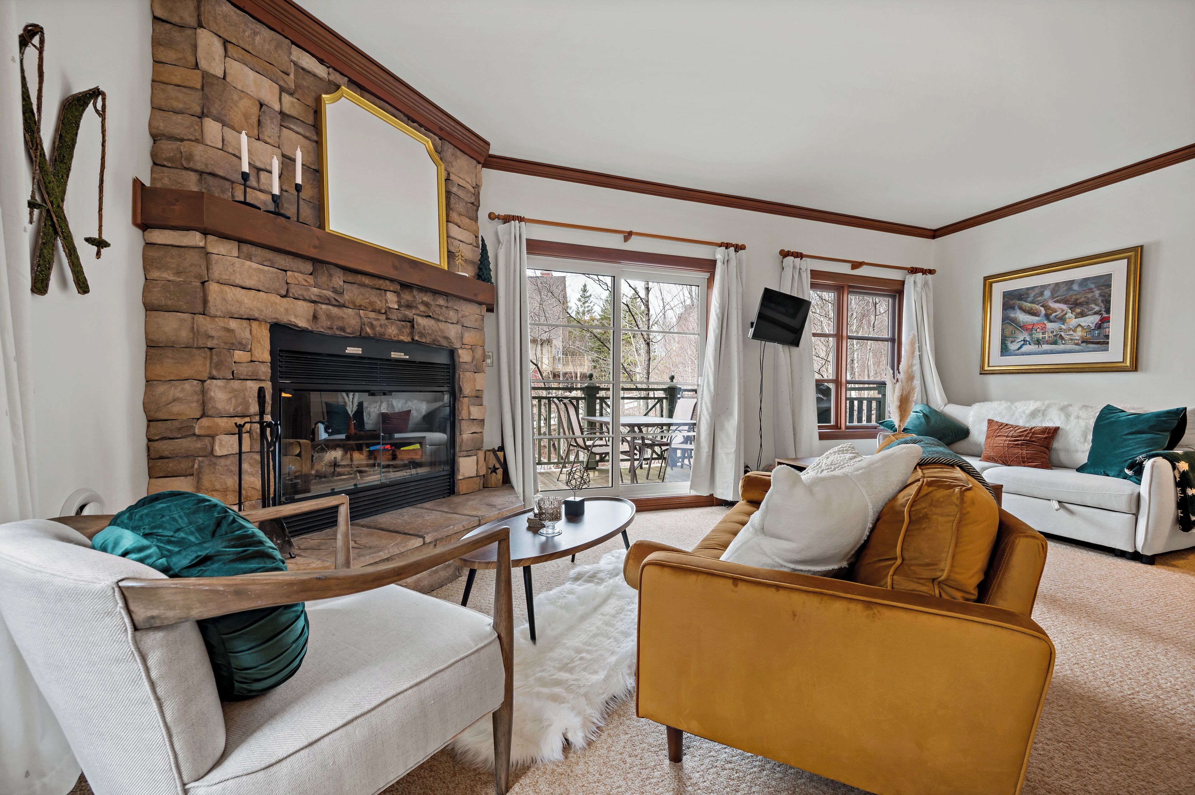 A cozy living room with a stone fireplace, a white sofa, a mustard-colored armchair, and a dining area with a table and chairs.