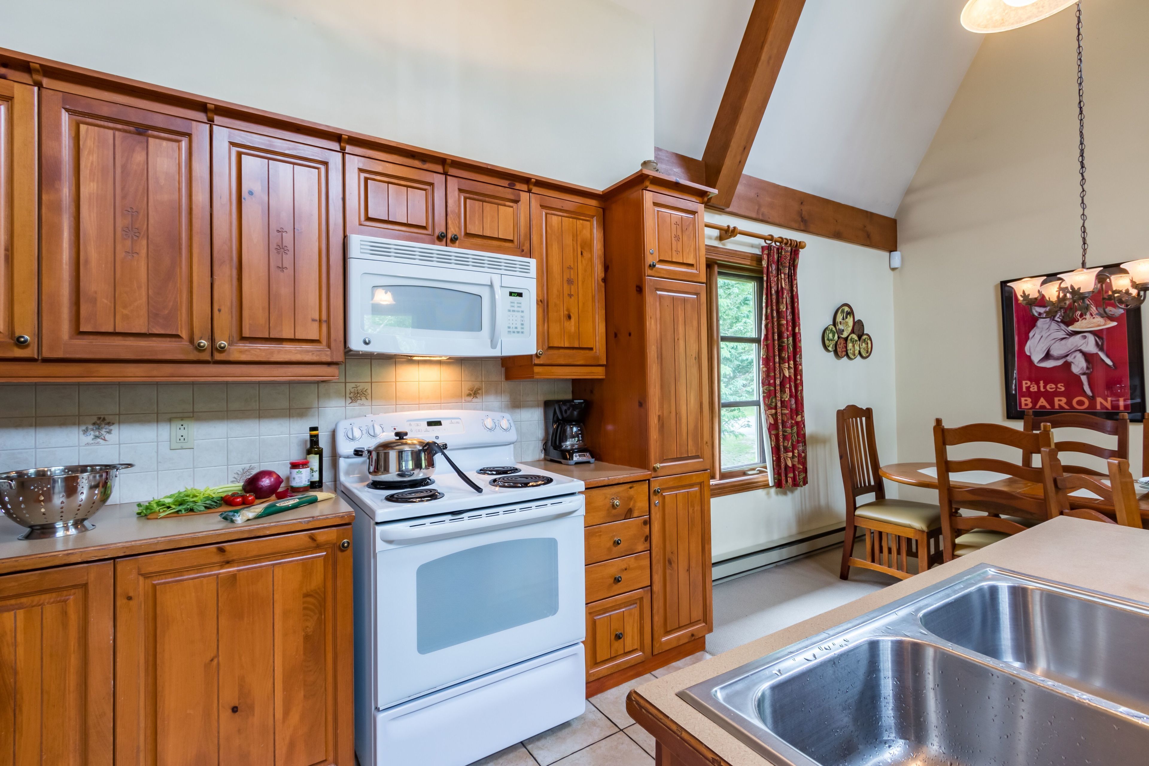 Une cuisine avec des meubles en bois, une cuisinière blanche et un évier en acier inoxydable.