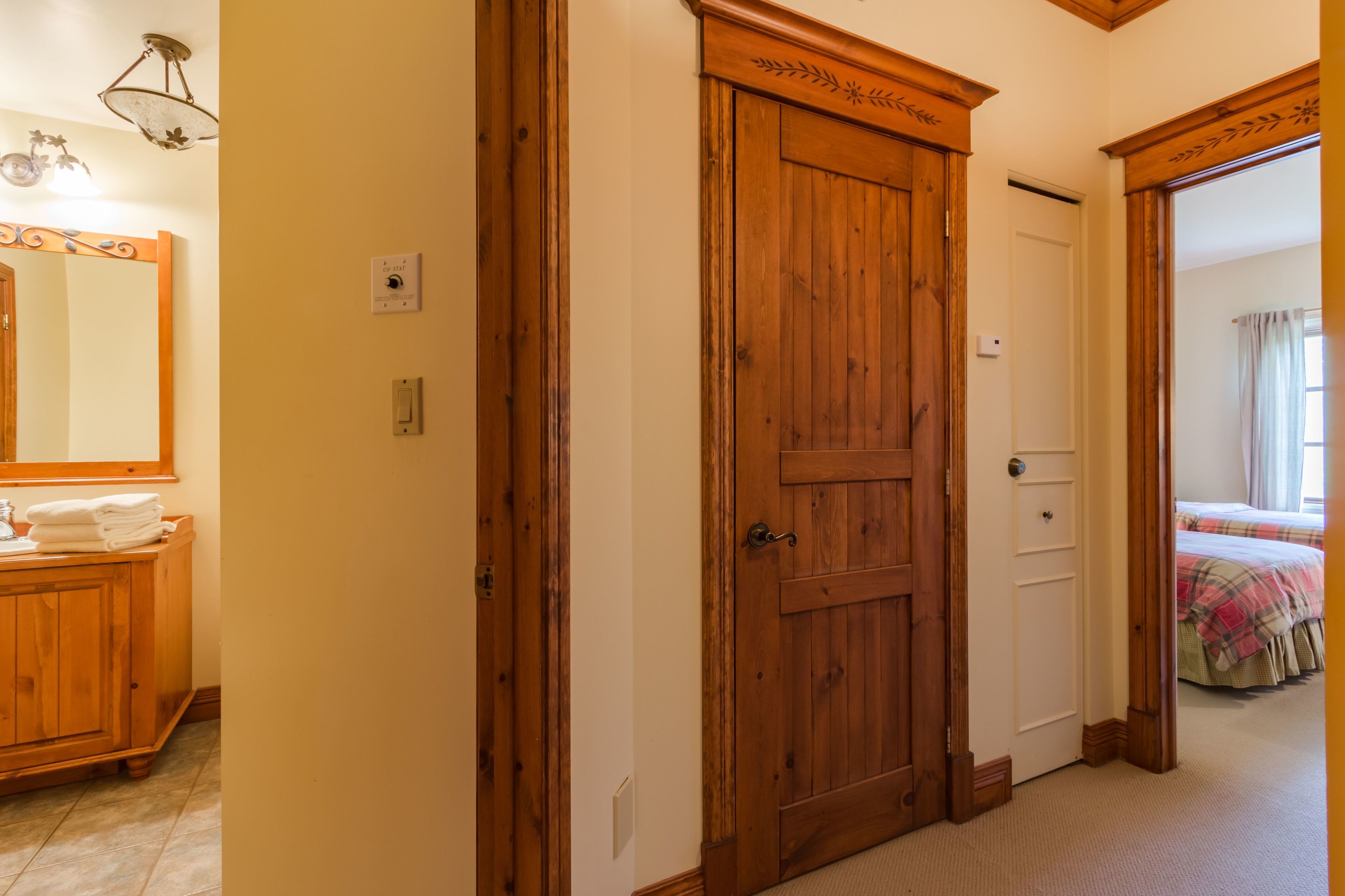 A wooden door with a decorative top, a mirror above it, and a wooden cabinet with folded towels.