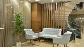 Un hall de diseño moderno, con un sofá blanco, una planta en maceta y un revestimiento de pared de madera.