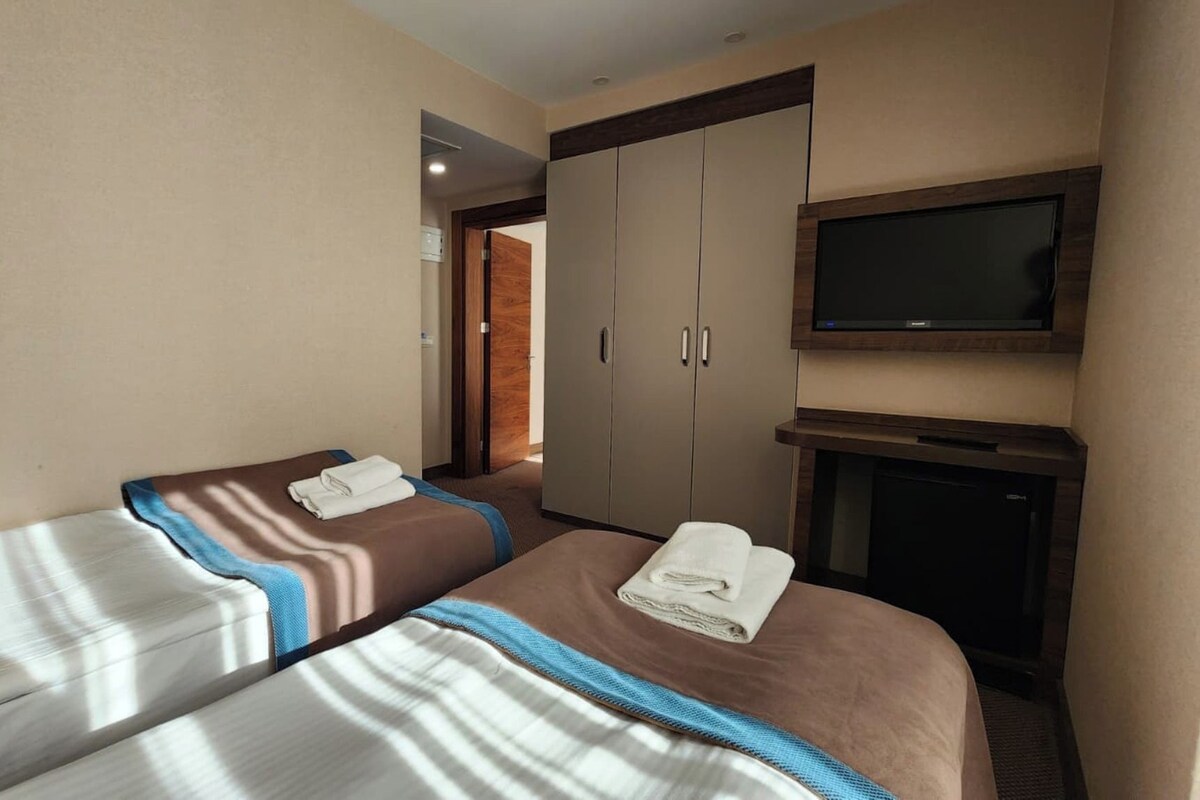 Ein Hotelzimmer mit zwei Betten, einem Fernseher und einem Kleiderschrank.