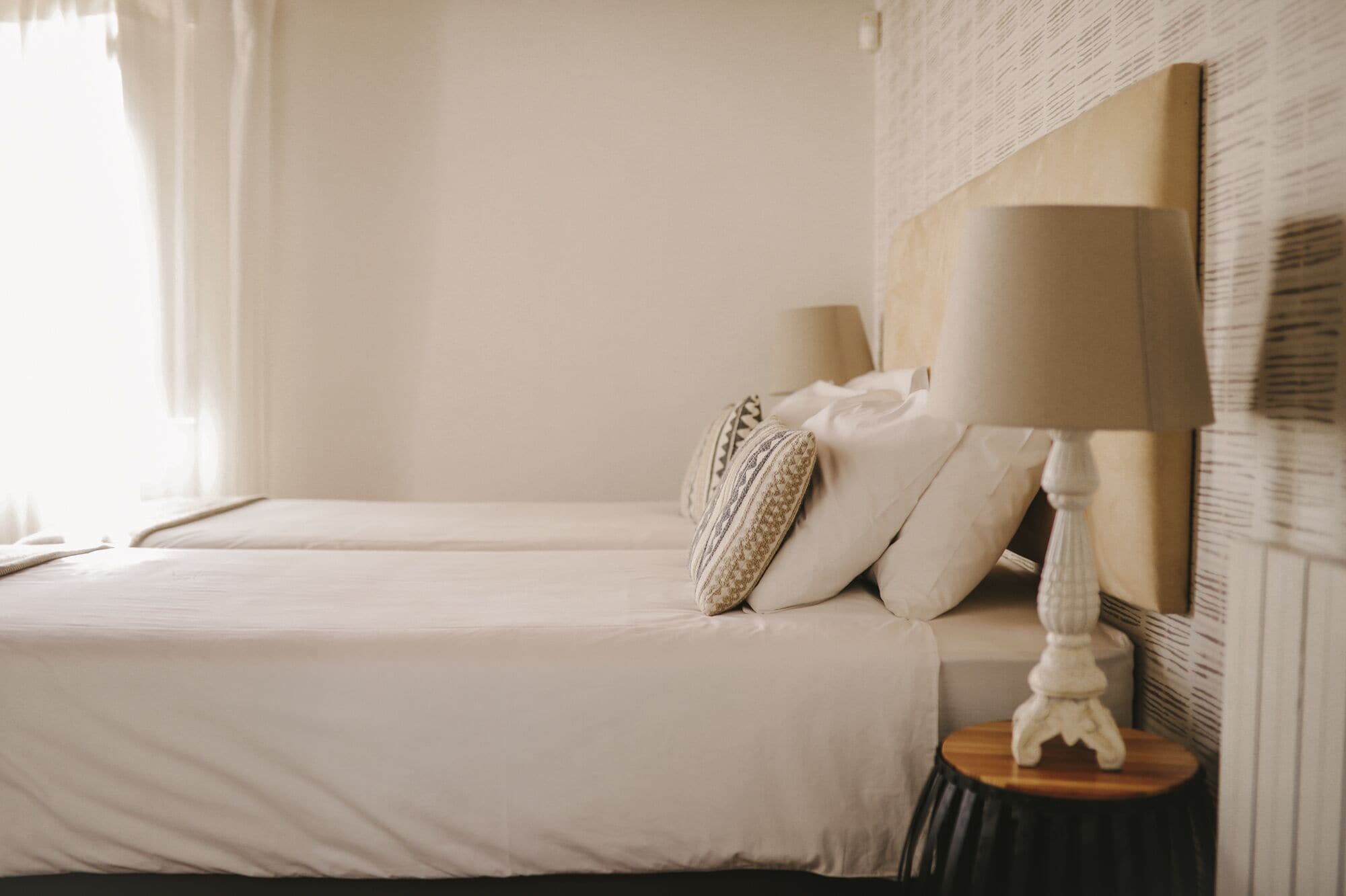 A hotel room with two beds, a bedside lamp, and a decorative wall piece.
