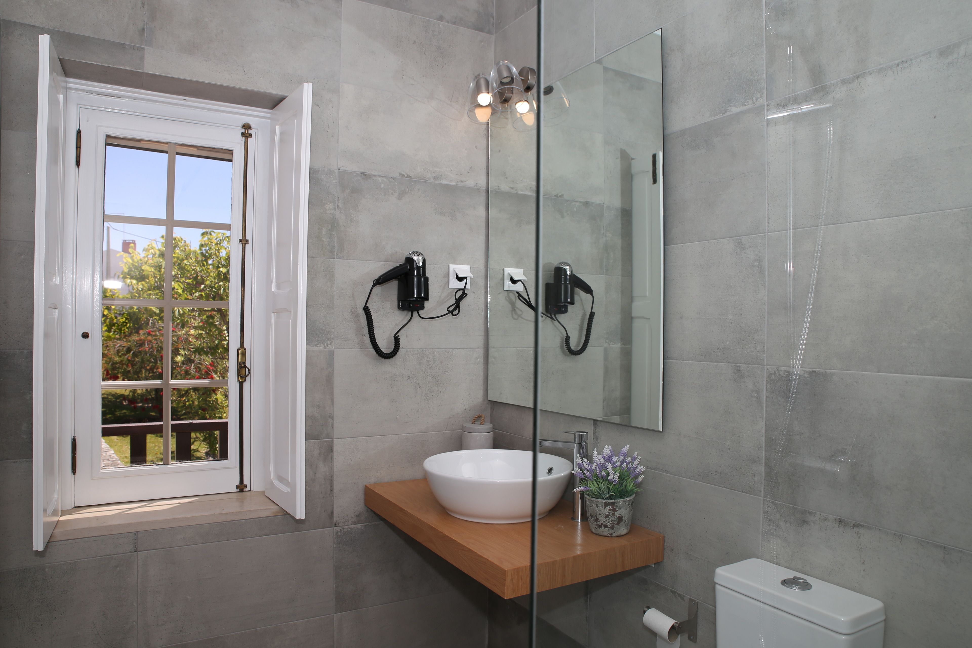 A bathroom with a white sink, a wooden countertop, a glass shower enclosure, and a large mirror.