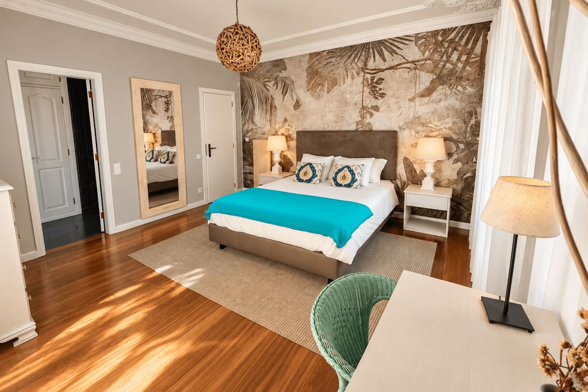 A modern bedroom with a large bed, two nightstands, a chair, and a decorative wall.
